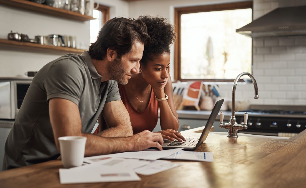 Couple looking at a laptop at the kitchen